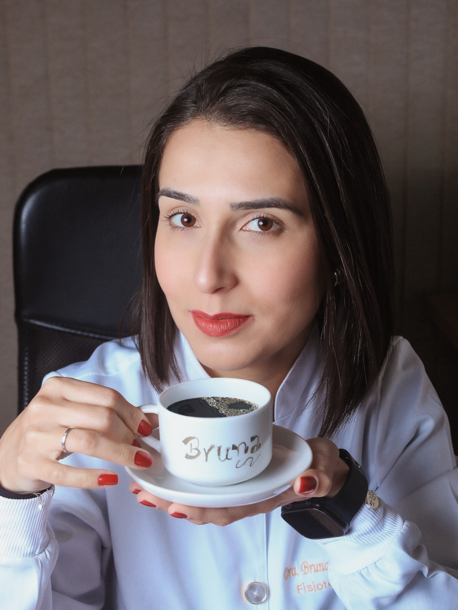 Bruna Iecker com jaleco branco segurando uma xícara de café.